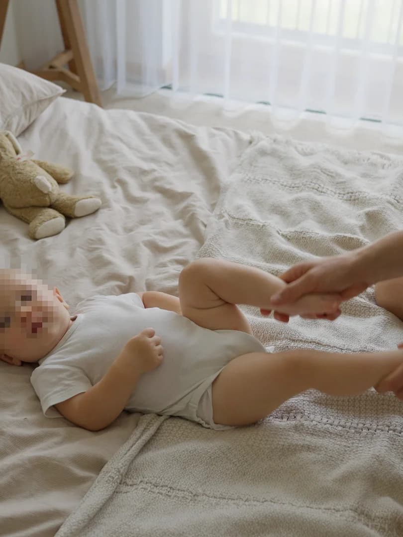 Parent gently guiding baby through bicycle kicks