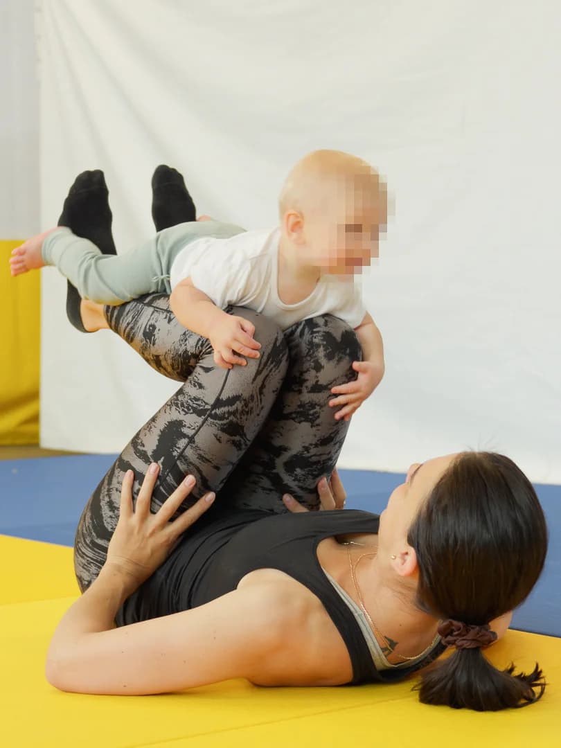 Parent doing flying baby exercise with smiling infant