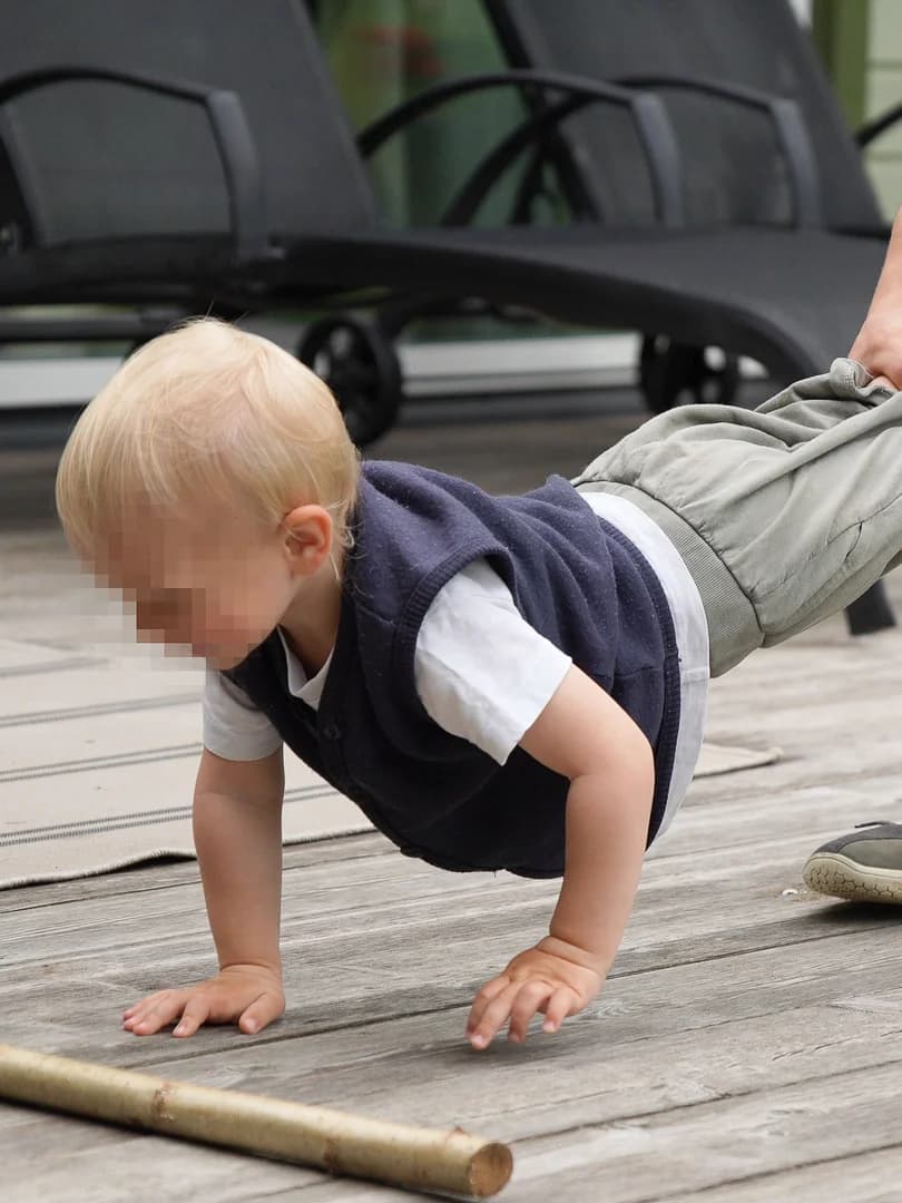 Baby doing wheelbarrow exercise supported by parent
