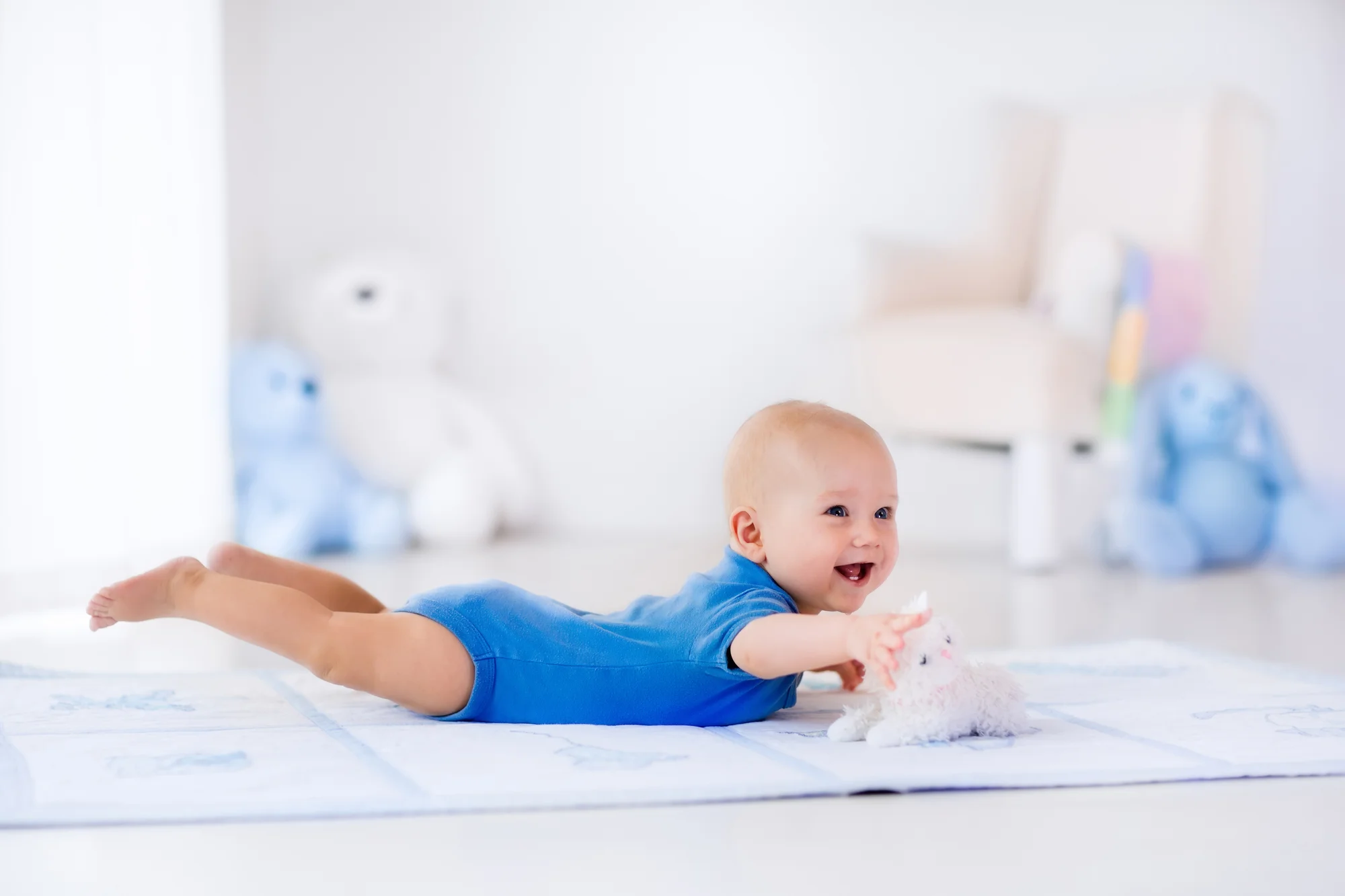 Newborn practicing tummy time on a plush mat while parent supervises