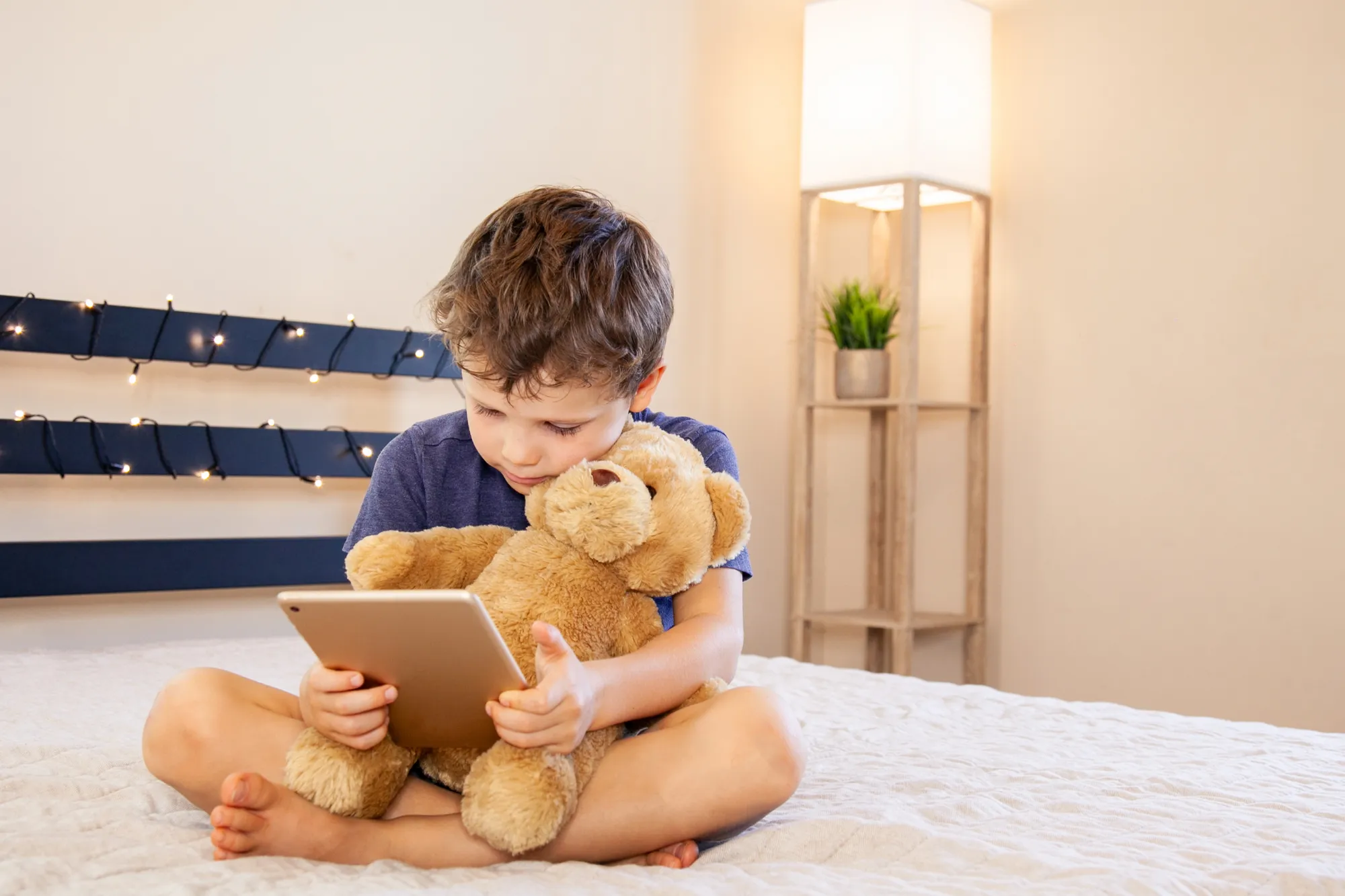 Boy with tablet computer in bed