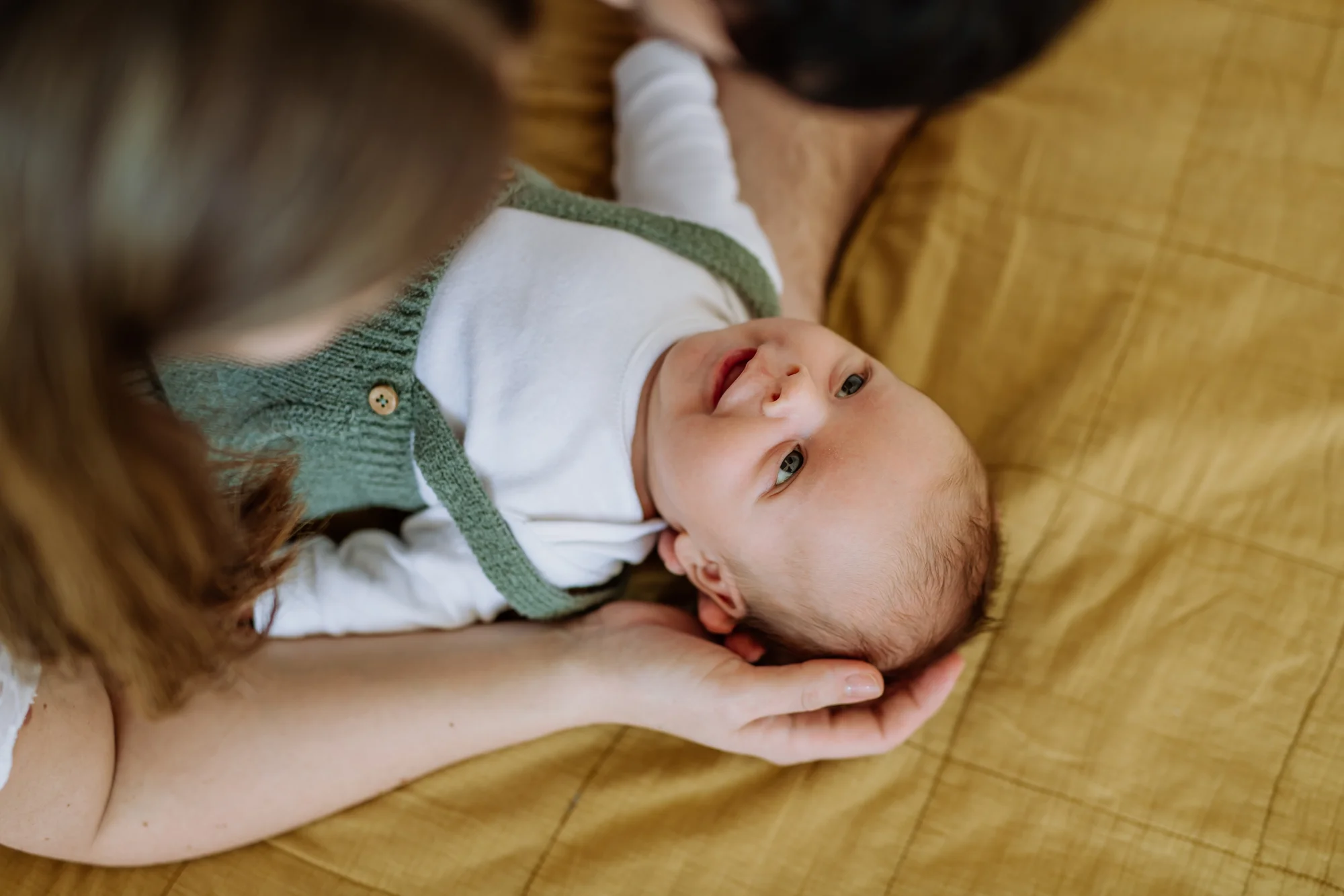 Parents cuddling their newborn while resting on the couch together