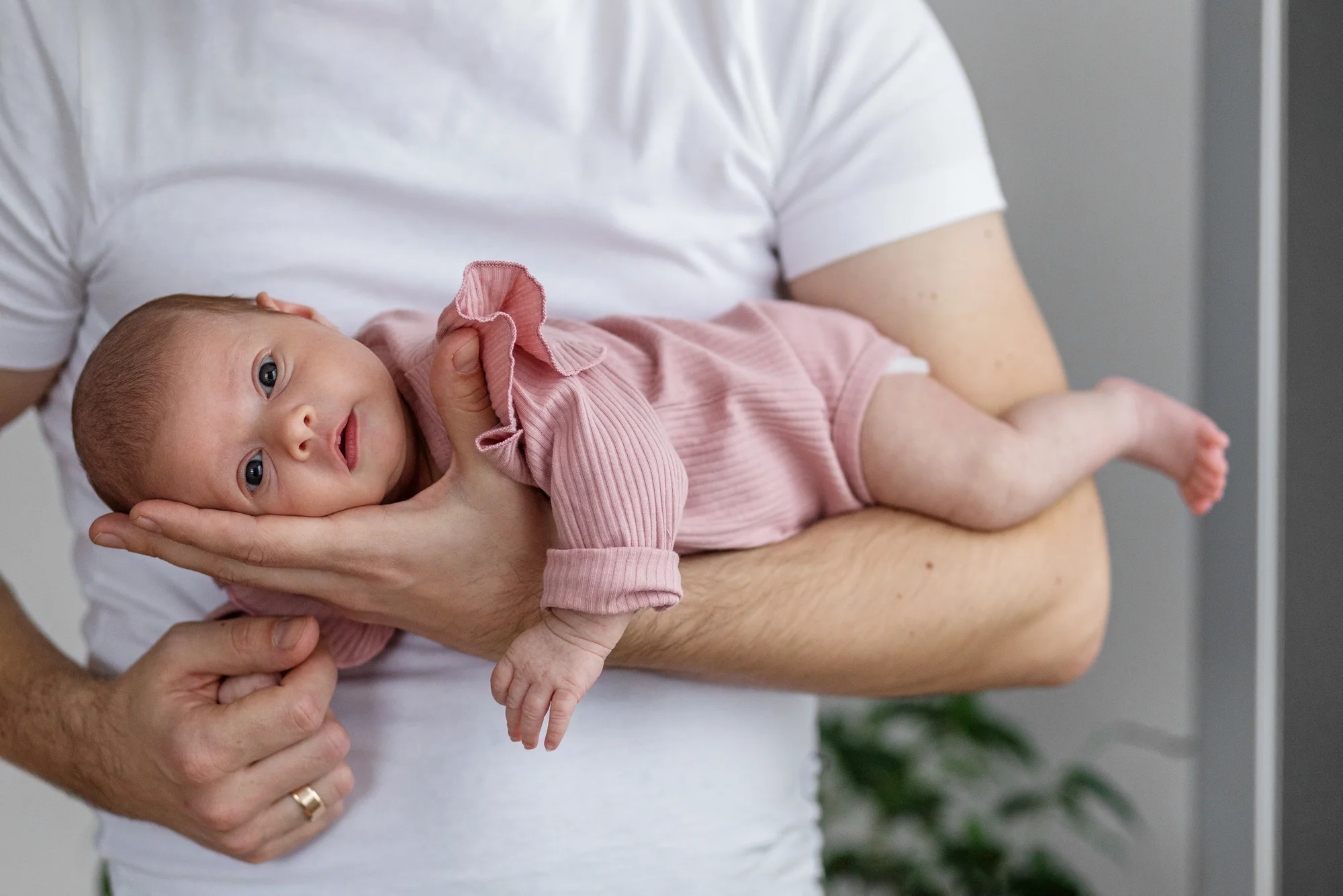 Parent supporting newborn in tiger-in-the-tree tummy time hold