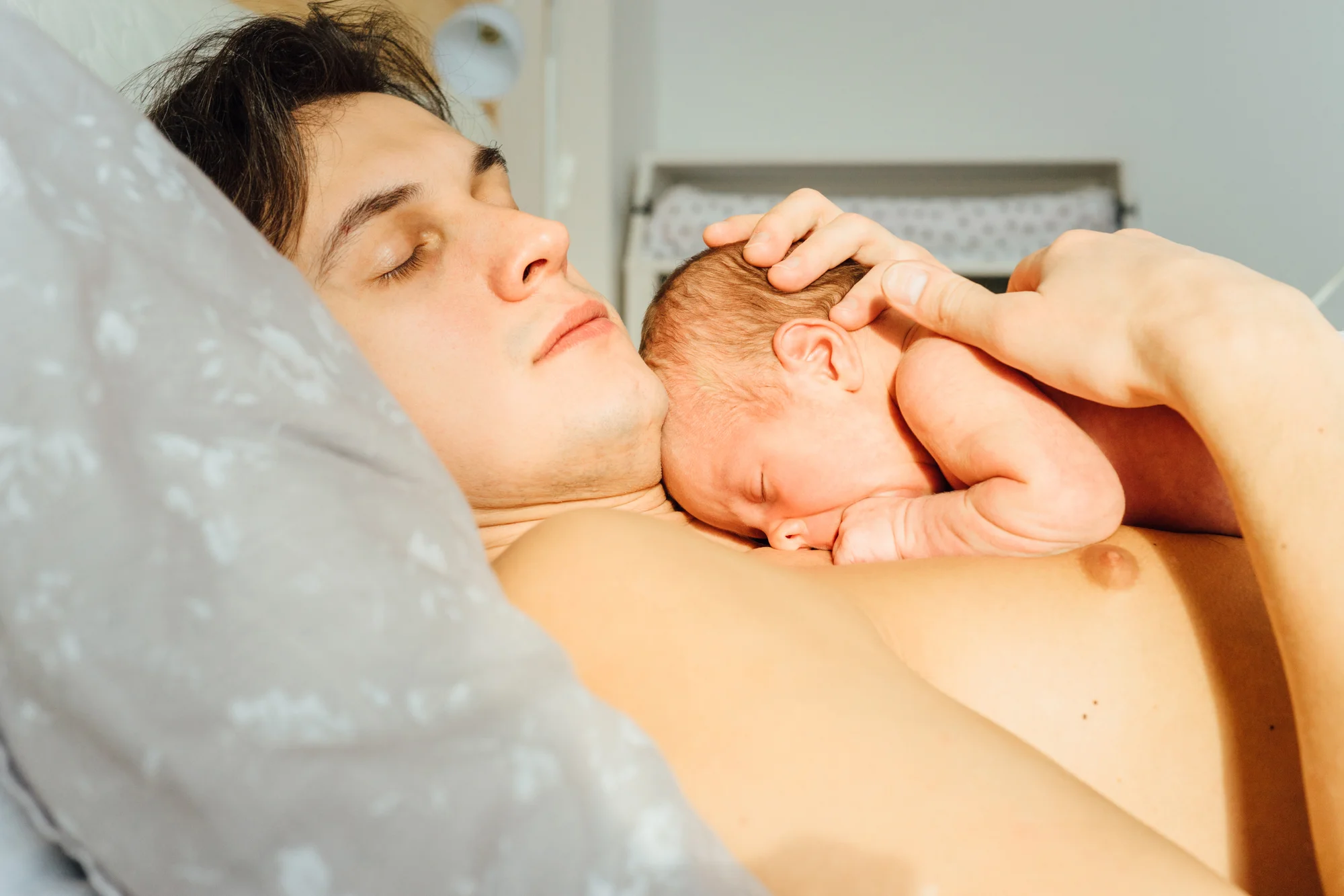 Father relaxing skin-to-skin with his newborn on his chest