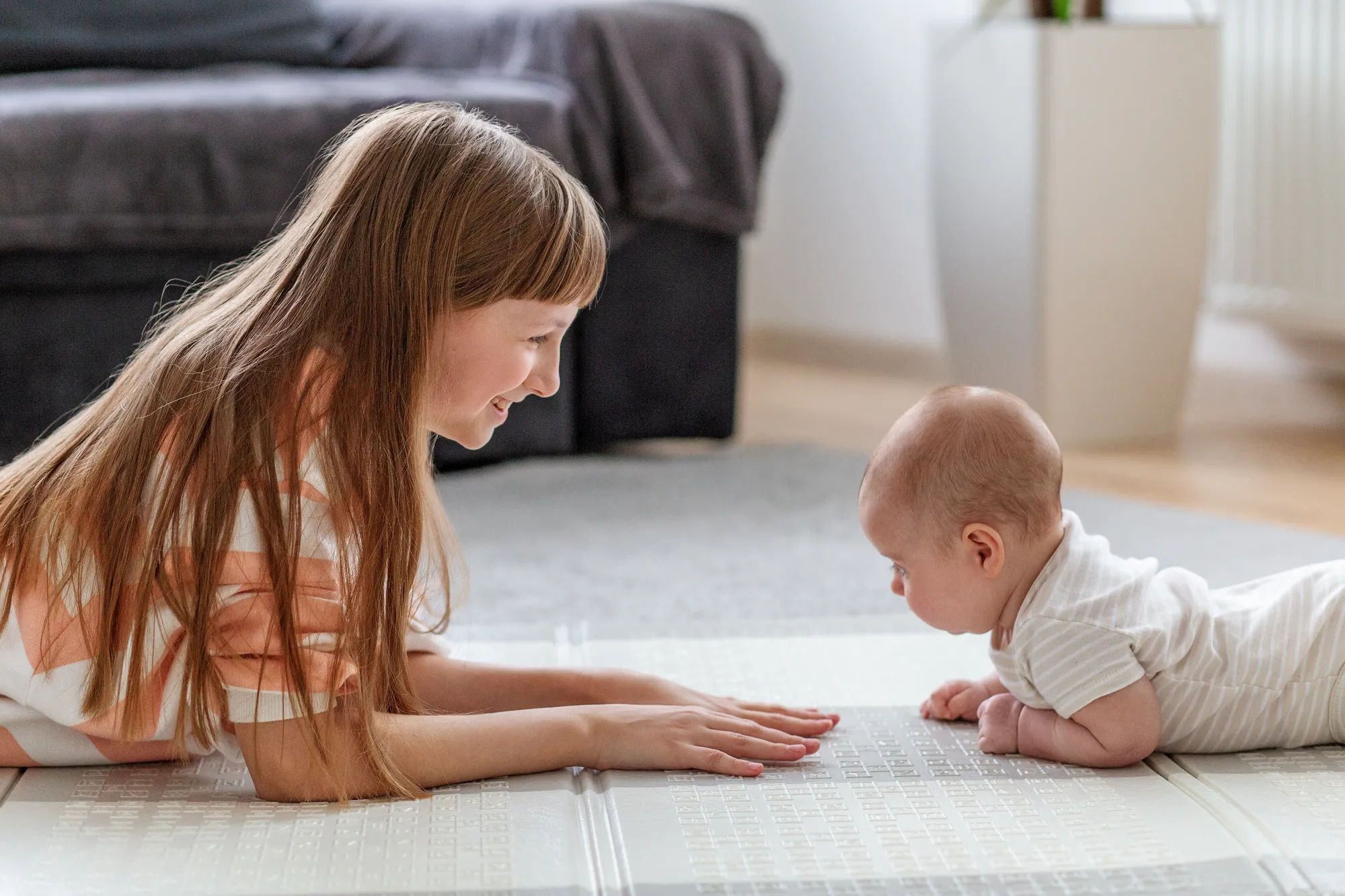 Sister helping baby with tummy time
