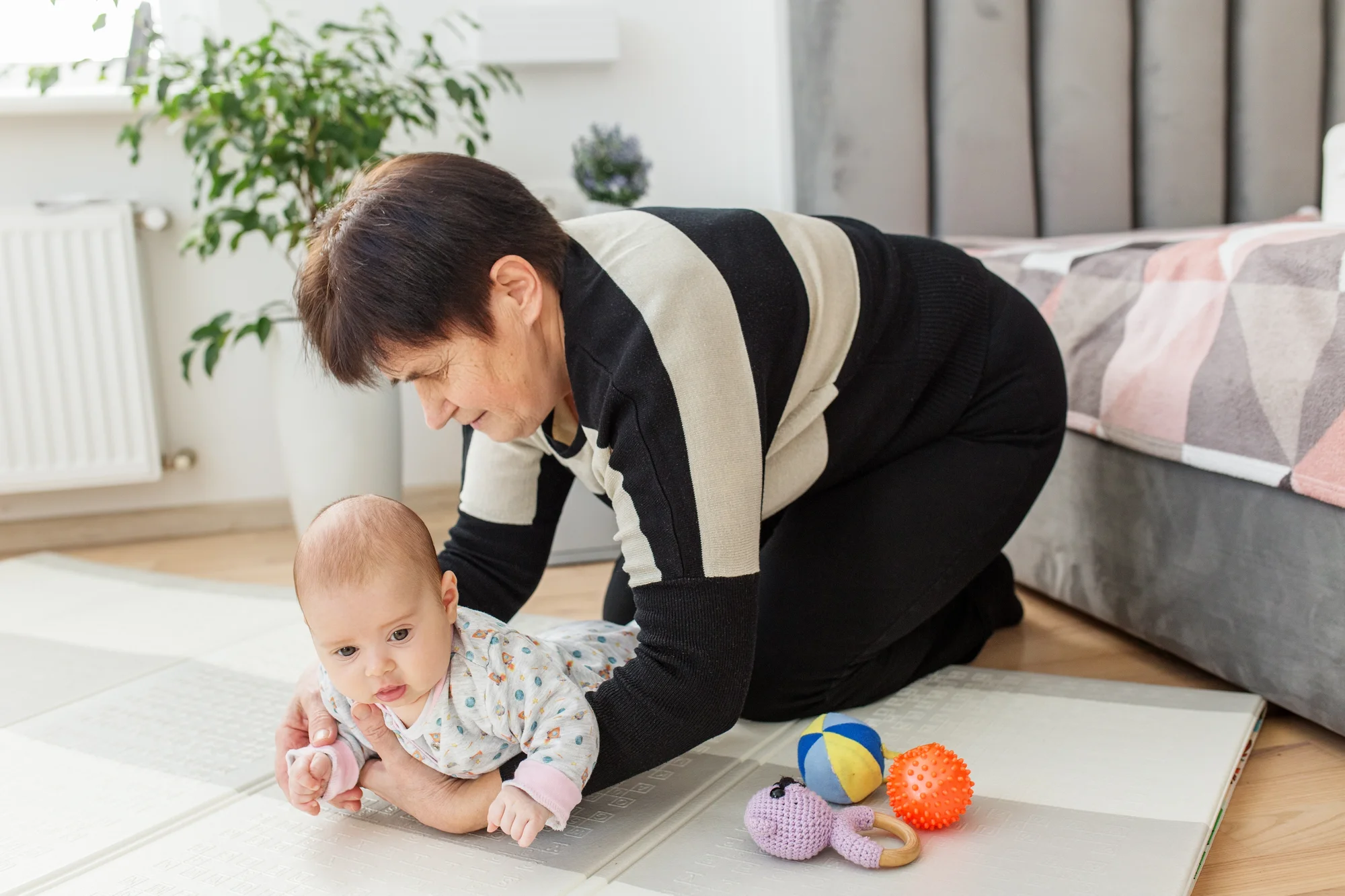 Grandmother supporting infant during tummy time with rolled towel