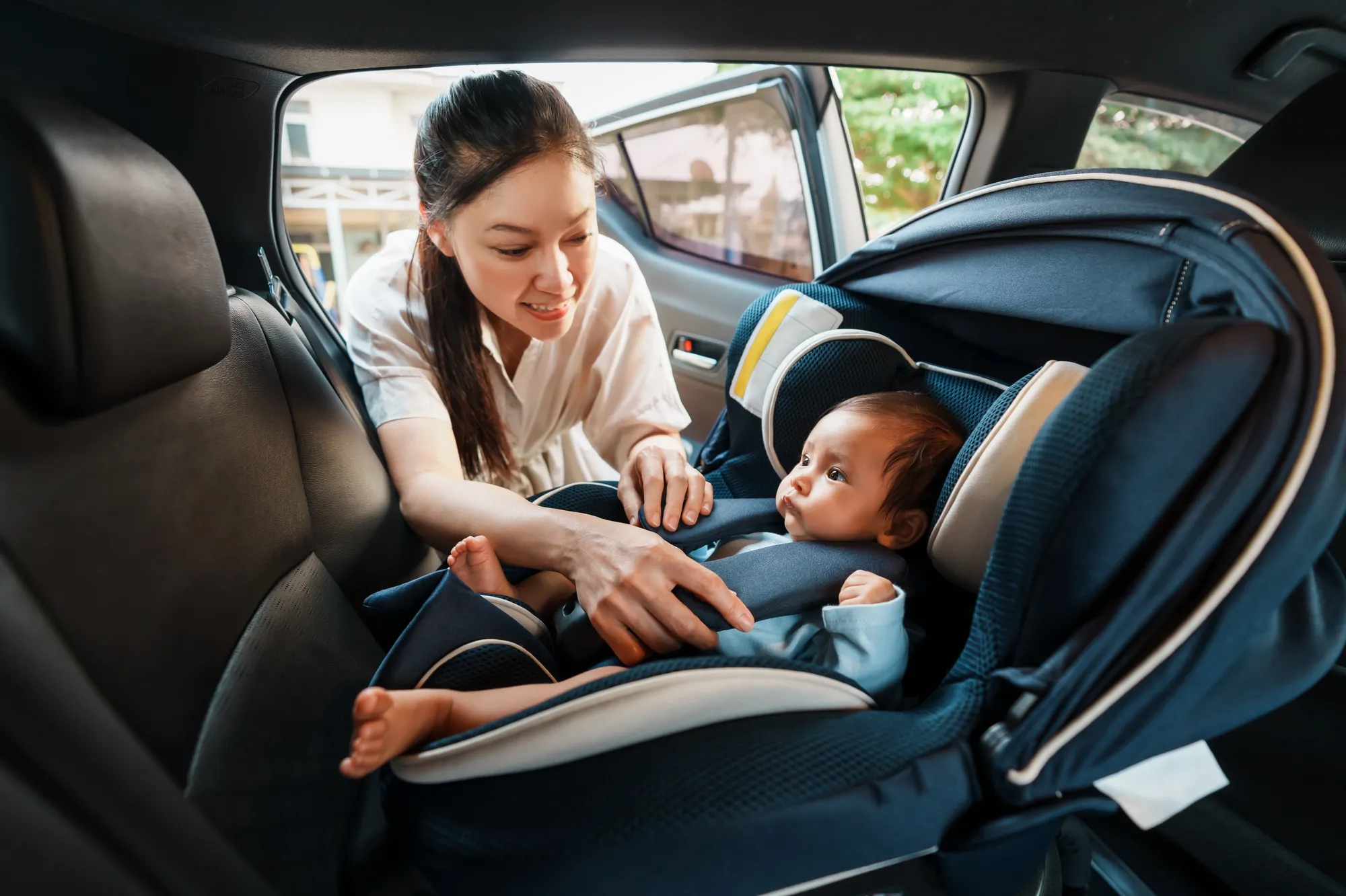Mother fastening baby in car seat