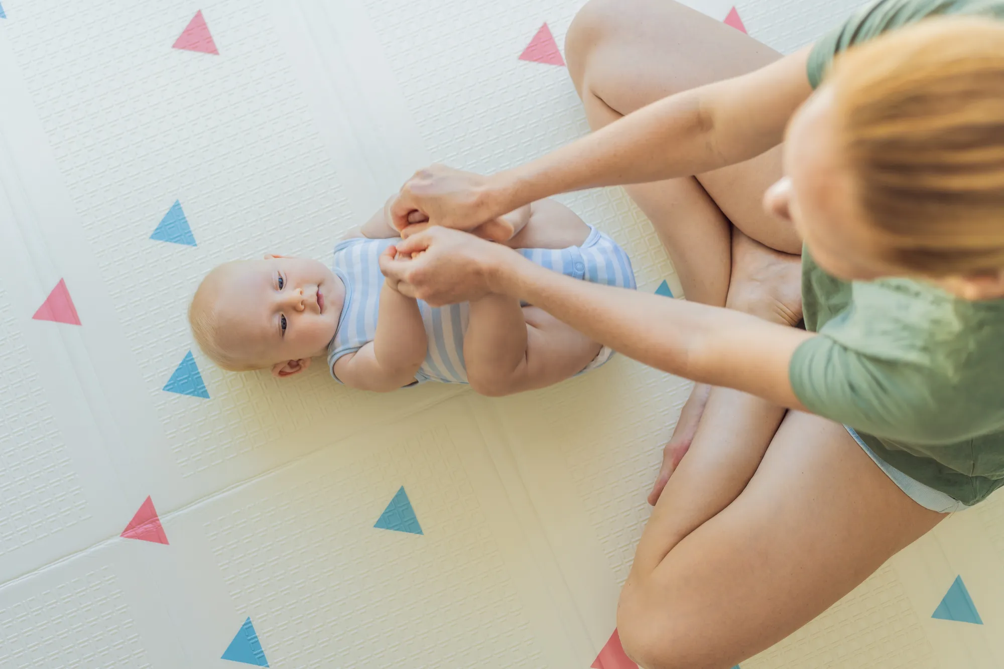 Mother doing exercises with baby on yoga mat