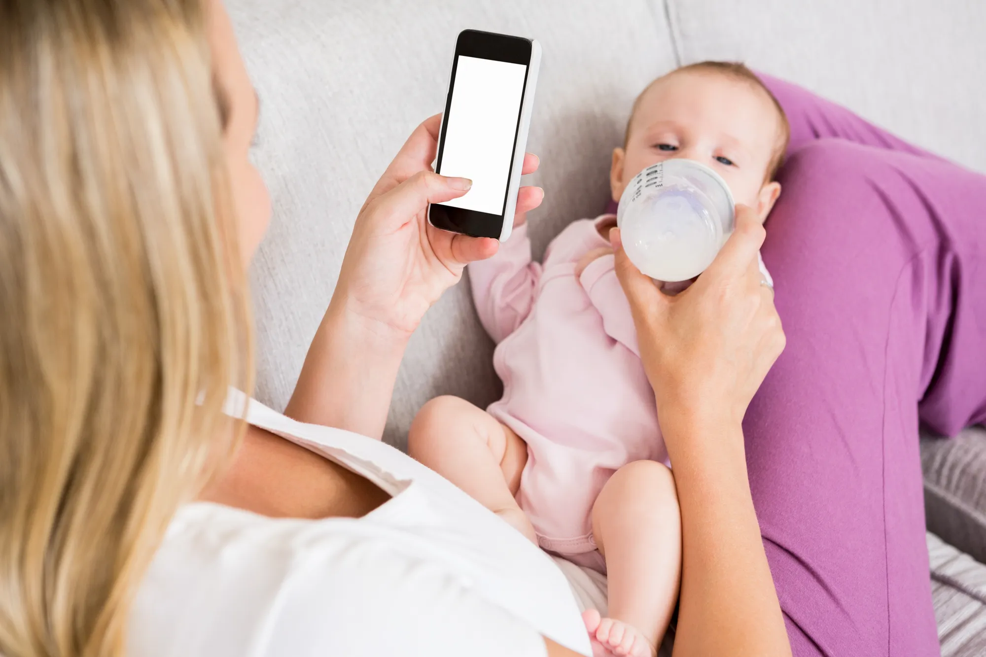 Mother using phone while feeding baby