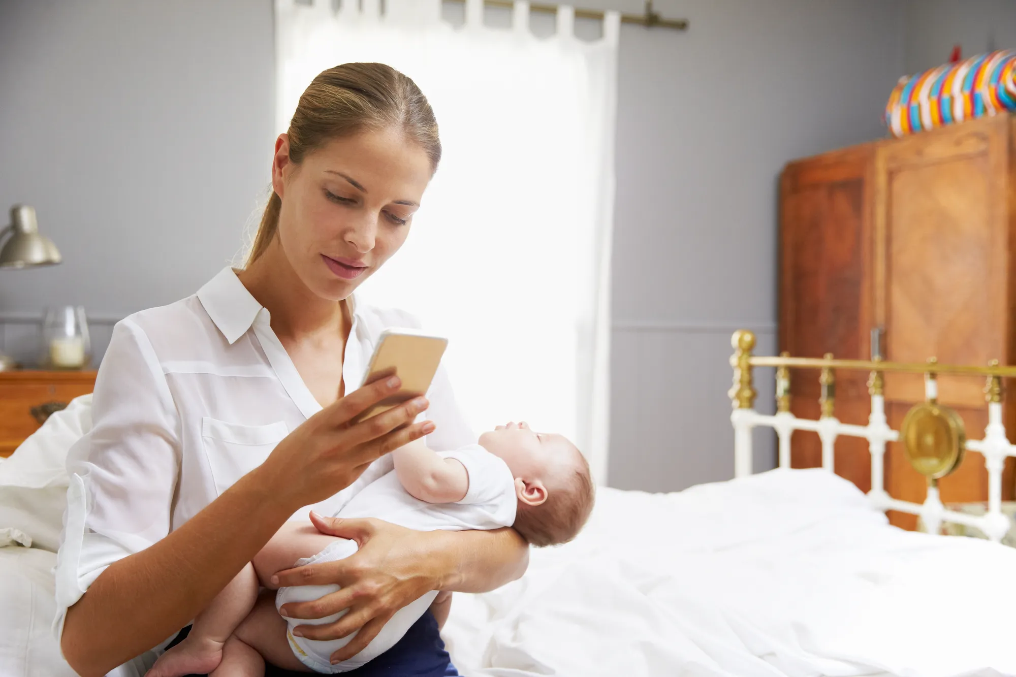 Working mother holding baby while checking phone